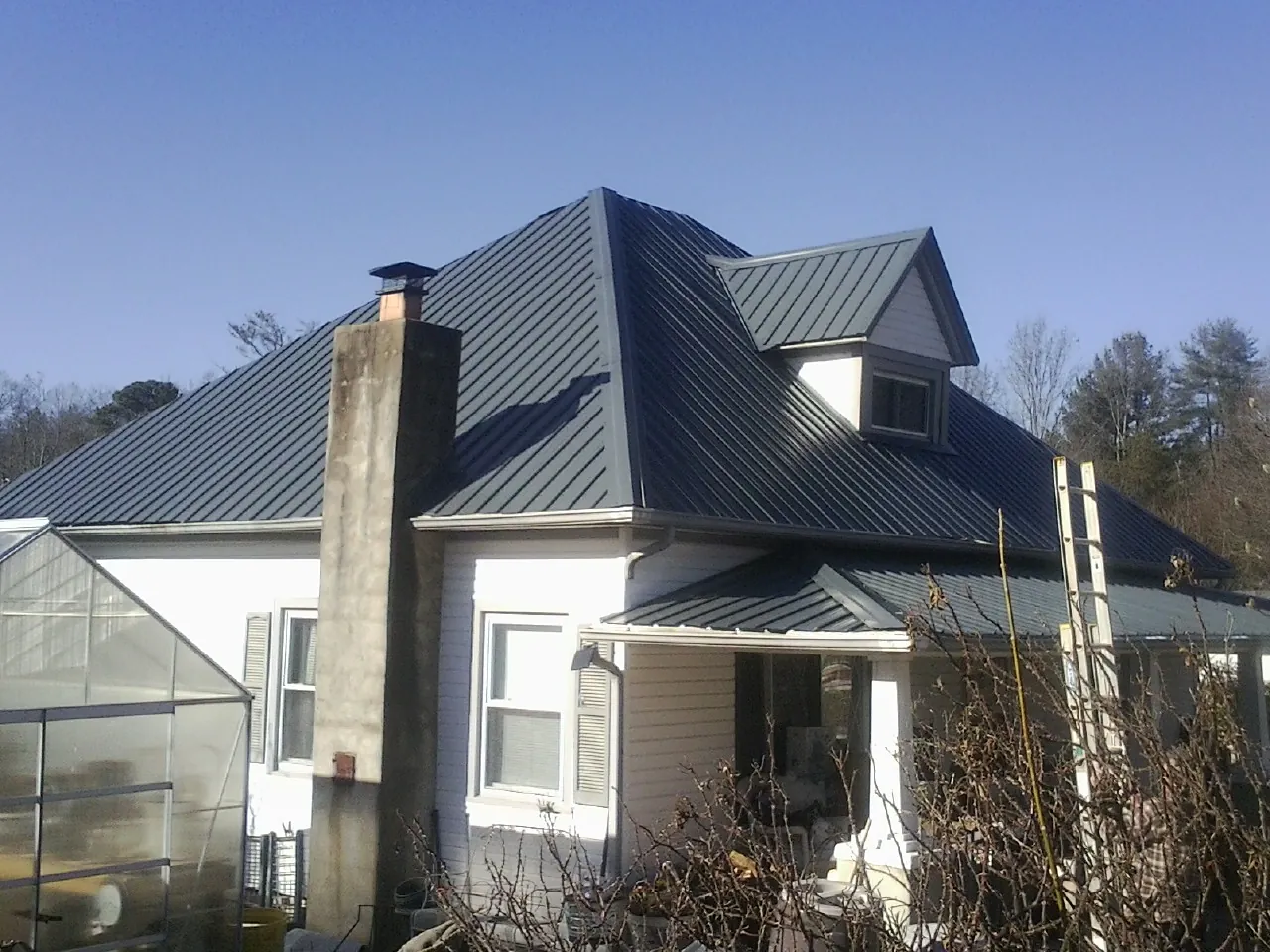 Dark blue standing seam metal roof on a white farmhouse with dormer — Slate & Tile Roof Repair by Roofing Brothers in Richeyville