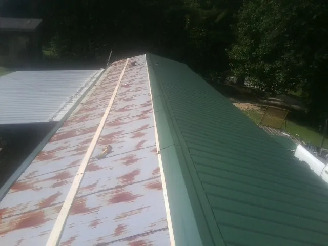 Old rusted panels beside newly installed green metal roofing — Wind Damage Roof Repair by Roofing Brothers in Richeyville