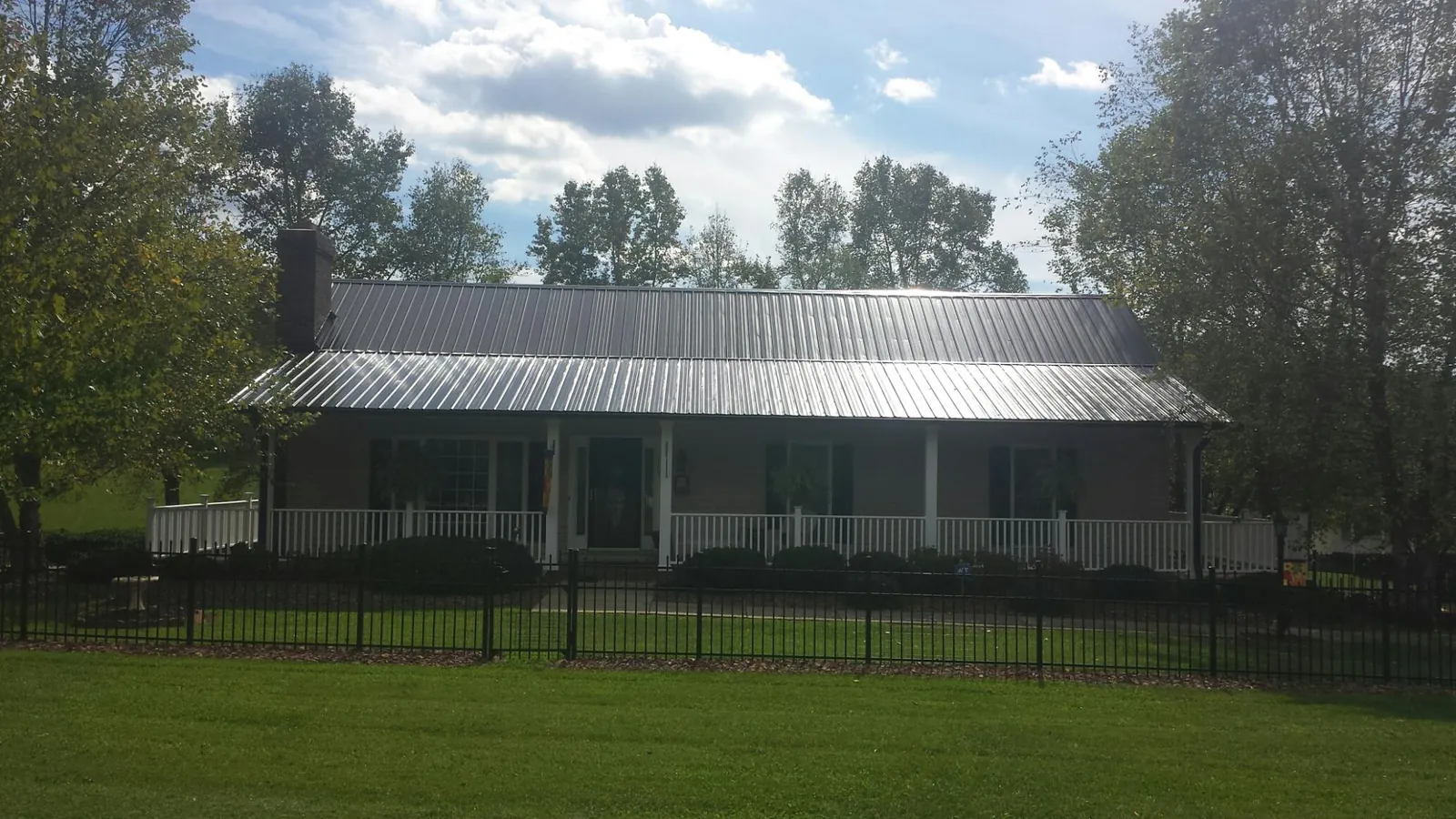 Gray metal roof on a brick ranch with a full width front porch — Gutter Guard Installation work by our crew in Richeyville