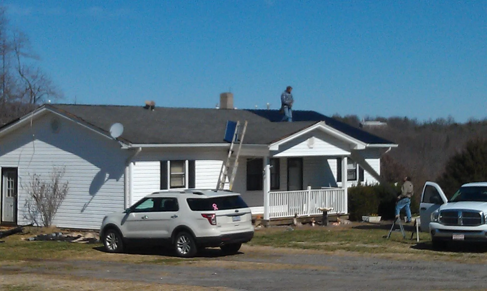 Roofers stripping shingles from a white ranch house roof in Richeyville