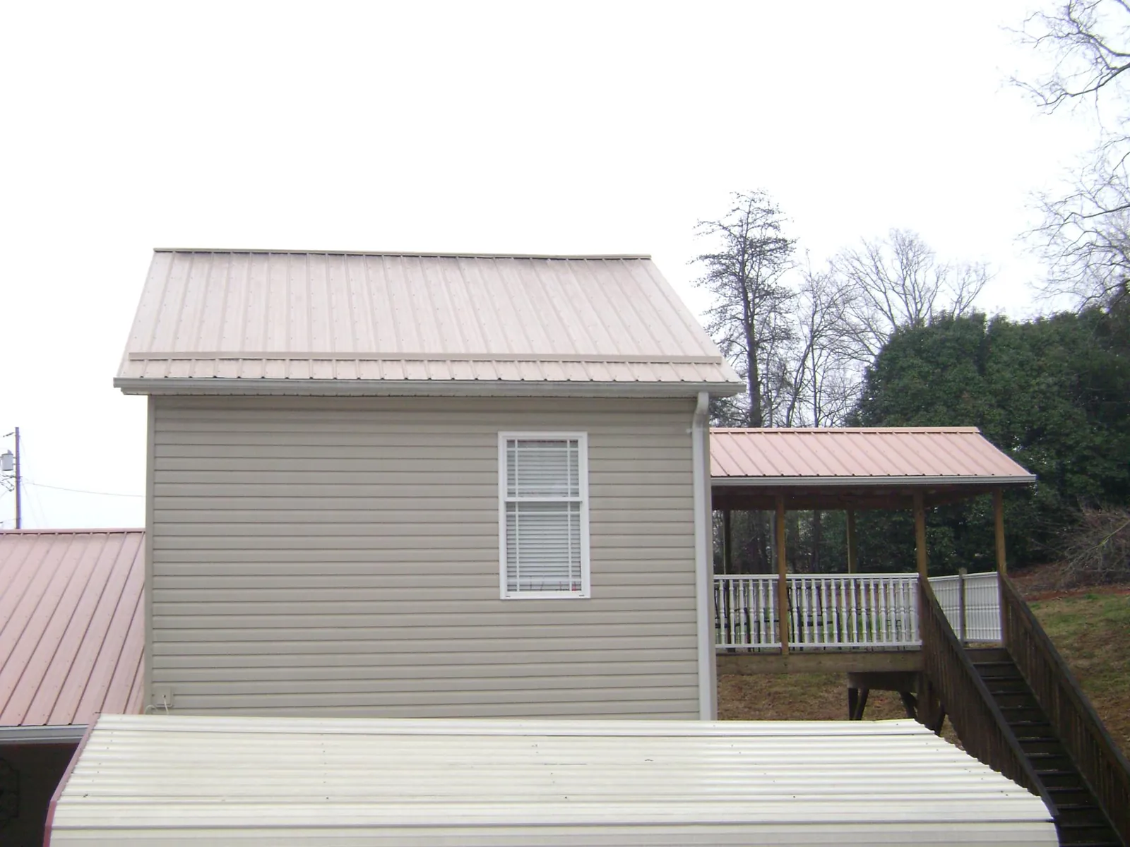 Tan metal roofs on a two story addition and attached porch, from a Roof Replacement job in Richeyville